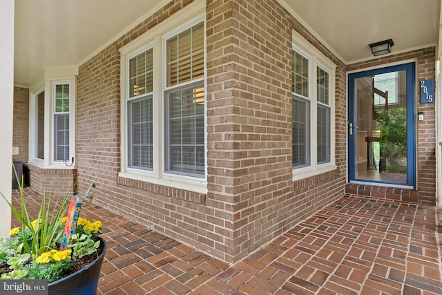 doorway to property featuring brick siding and covered porch