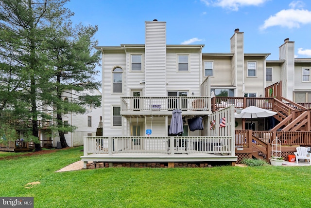 rear view of property featuring a lawn, a chimney, and a deck