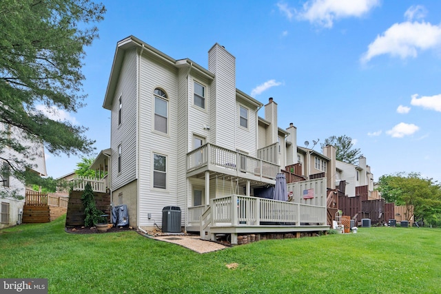 rear view of house featuring a deck, a yard, central AC, and a chimney