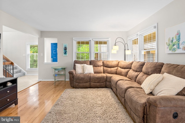 living room with stairway, light wood-style flooring, and baseboards