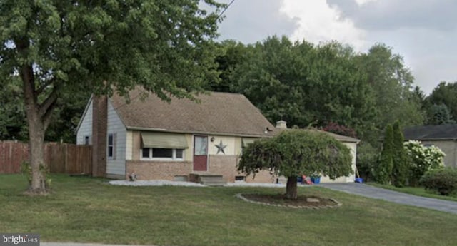 view of front of property with driveway, a chimney, fence, and a front lawn