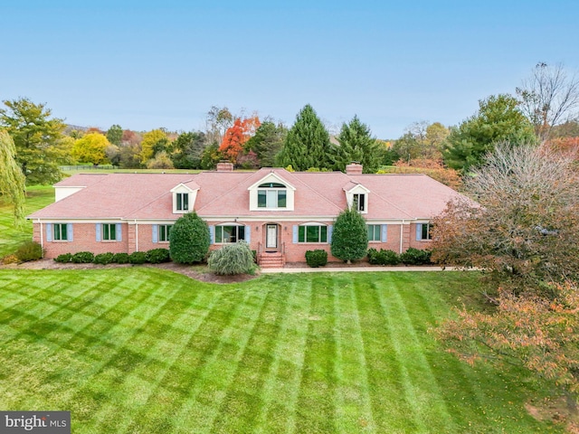 back of house featuring a yard, brick siding, and a chimney