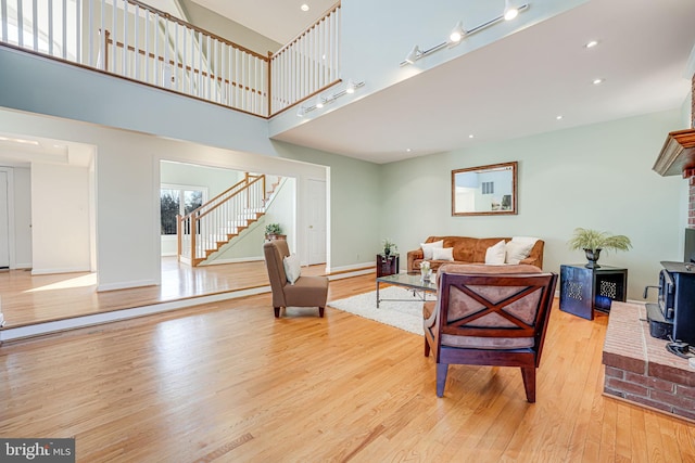 living area with baseboards, a wood stove, recessed lighting, stairs, and light wood-style floors