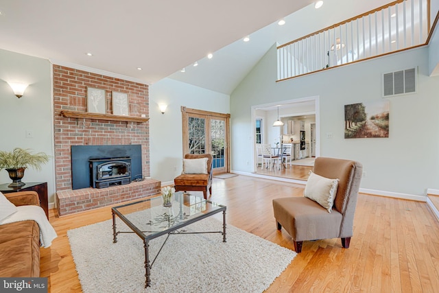 living room with visible vents, baseboards, high vaulted ceiling, and light wood-style flooring