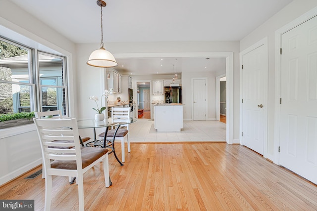 dining room featuring light wood-type flooring, baseboards, and visible vents