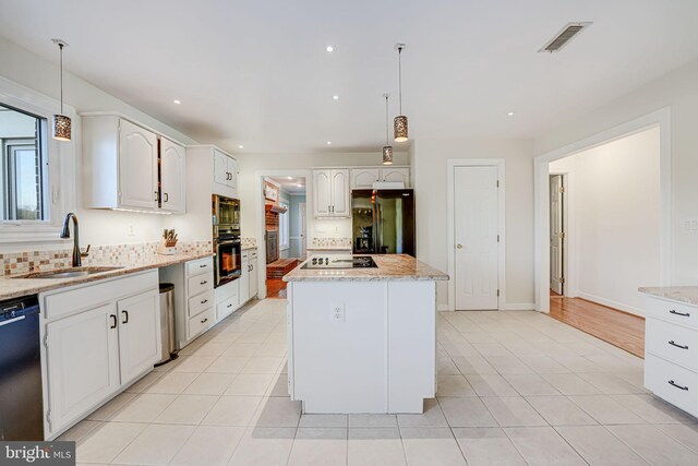 kitchen featuring visible vents, black appliances, a sink, tasteful backsplash, and a center island