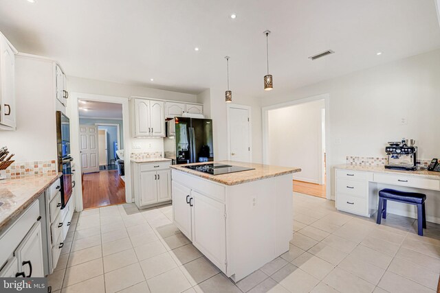 kitchen with decorative backsplash, black appliances, a center island, and visible vents