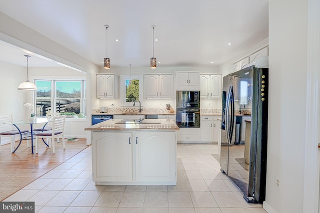 kitchen featuring pendant lighting, a kitchen island, black appliances, and white cabinetry