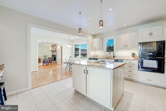 kitchen with light tile patterned floors, white cabinetry, a center island, and black appliances