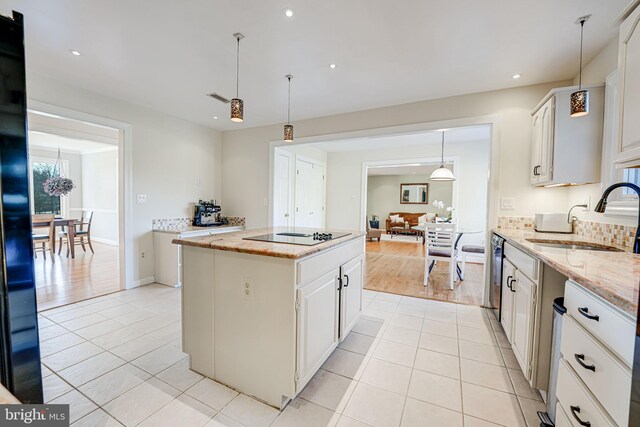 kitchen featuring a kitchen island, light tile patterned flooring, a sink, black appliances, and white cabinetry