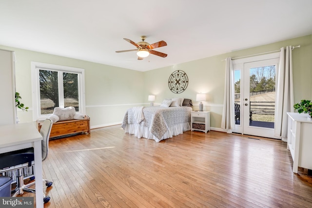 bedroom with hardwood / wood-style flooring, access to outside, multiple windows, and baseboards