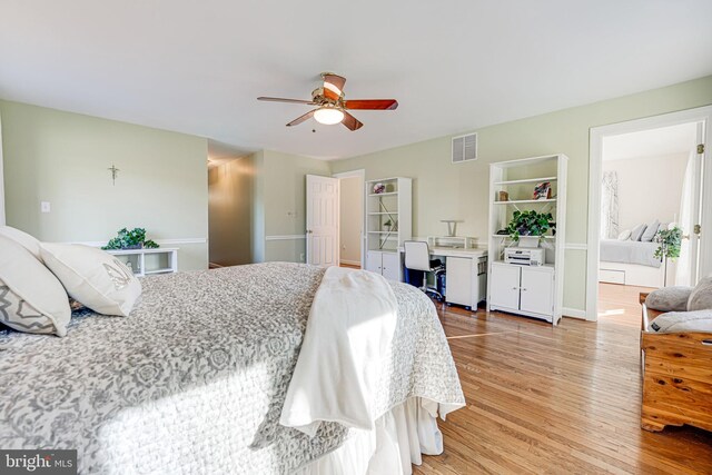 bedroom featuring light wood finished floors, visible vents, and a ceiling fan