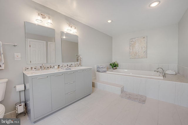 full bath featuring a sink, a garden tub, toilet, and double vanity