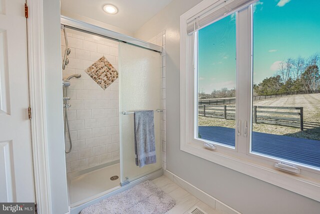 full bathroom with a shower stall and baseboards