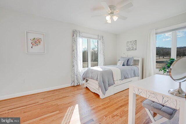 bedroom with light wood-style flooring, baseboards, and ceiling fan