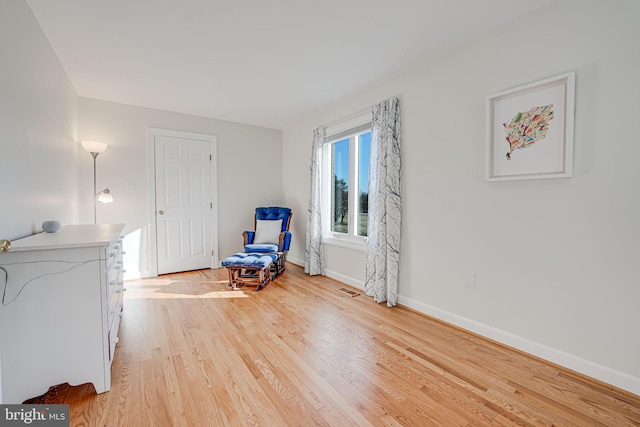 living area featuring light wood-type flooring, baseboards, and visible vents