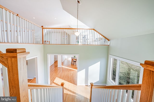 staircase with recessed lighting, a towering ceiling, and wood finished floors