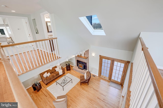 living room with wood finished floors, a skylight, a fireplace, and a healthy amount of sunlight