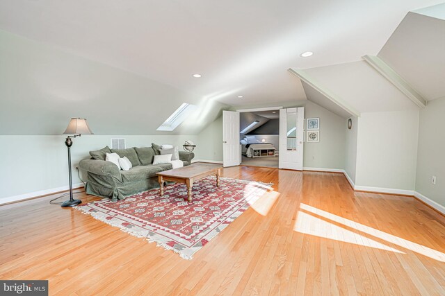 living area with visible vents, lofted ceiling with skylight, wood finished floors, recessed lighting, and baseboards