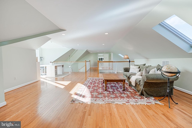 living room featuring visible vents, lofted ceiling with skylight, hardwood / wood-style floors, recessed lighting, and baseboards