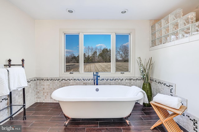 bathroom with a freestanding tub, tile walls, and wood tiled floor