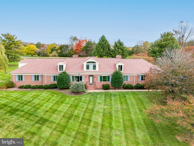 rear view of property with brick siding, a chimney, and a yard