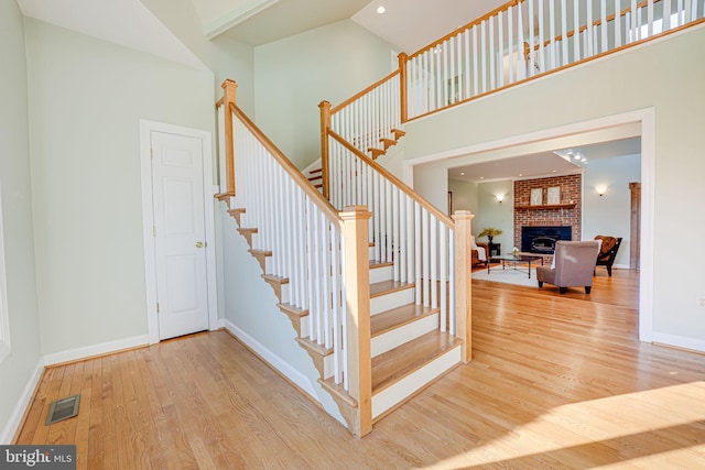 stairs with wood finished floors, visible vents, a towering ceiling, and baseboards