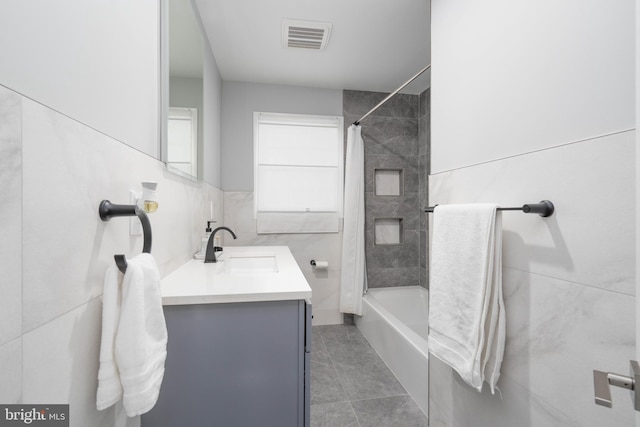 full bath with vanity, visible vents, tile patterned flooring, tile walls, and shower / tub combo with curtain