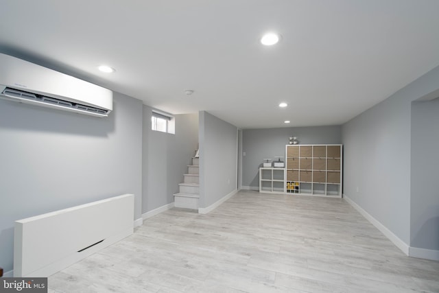 basement with a wall unit AC, baseboards, light wood-style flooring, recessed lighting, and stairs