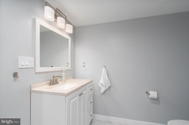 half bath with vanity, baseboards, and marble finish floor