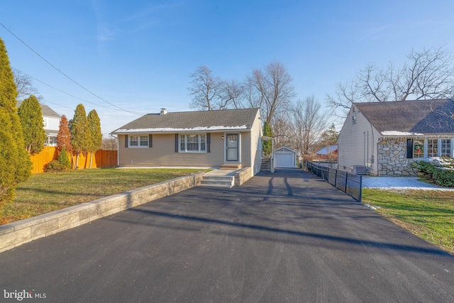 view of front of house featuring fence, driveway, an outdoor structure, a front lawn, and a detached garage