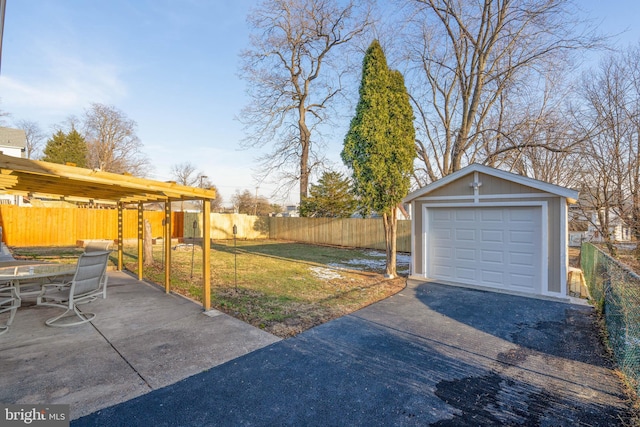 view of yard with a garage, driveway, fence private yard, and an outdoor structure