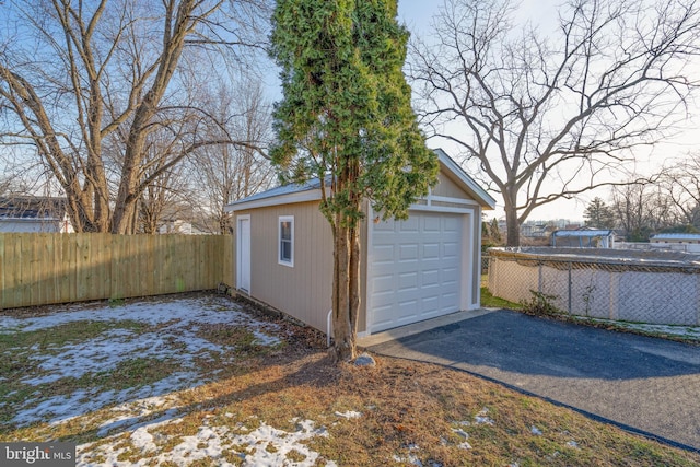 detached garage featuring driveway and fence