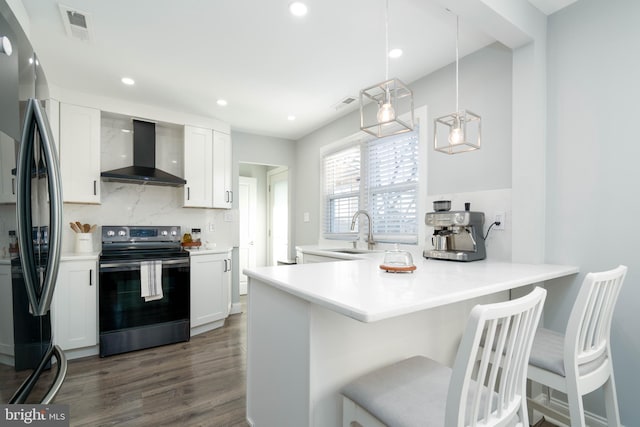 kitchen featuring visible vents, a sink, decorative backsplash, appliances with stainless steel finishes, and wall chimney range hood