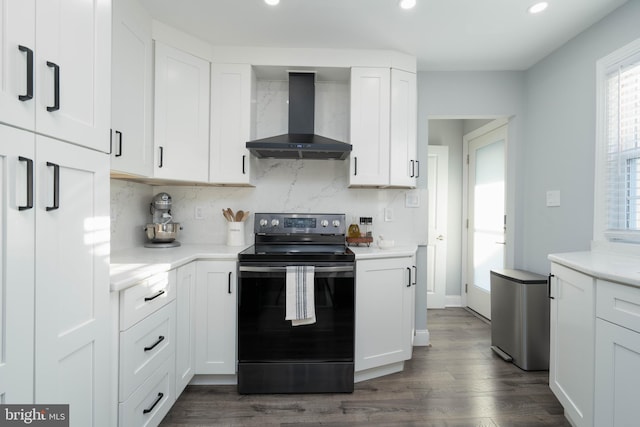 kitchen with black / electric stove, dark wood-style floors, white cabinetry, wall chimney exhaust hood, and backsplash