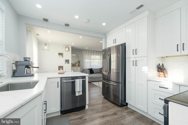 kitchen with visible vents, appliances with stainless steel finishes, wood finished floors, white cabinets, and a sink