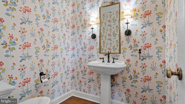 bathroom featuring toilet, wallpapered walls, baseboards, and wood finished floors