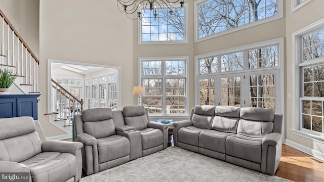 living area featuring wood finished floors, visible vents, baseboards, stairs, and a notable chandelier