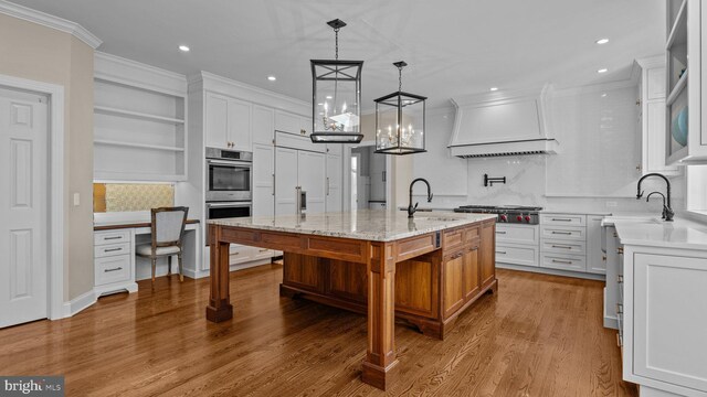 kitchen featuring stainless steel appliances, crown molding, custom range hood, and a sink