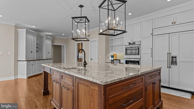 kitchen featuring light wood-type flooring, ornamental molding, a sink, double oven, and white cabinets