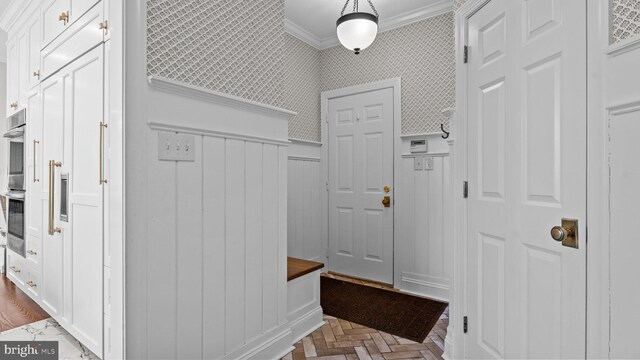 mudroom with wainscoting, wallpapered walls, and crown molding