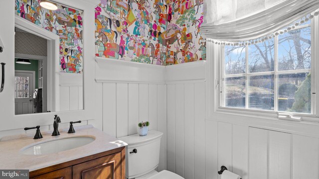 half bathroom featuring wainscoting, toilet, and vanity