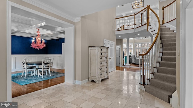 tiled entryway with a chandelier, beam ceiling, coffered ceiling, and crown molding