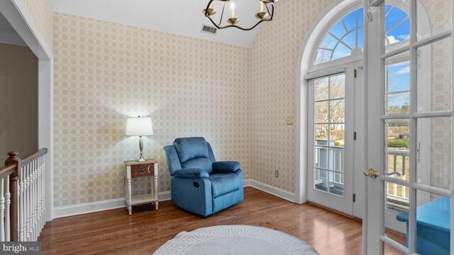 living area featuring visible vents, wallpapered walls, baseboards, and wood finished floors