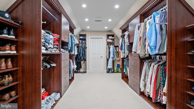 spacious closet with visible vents, lofted ceiling, and carpet flooring