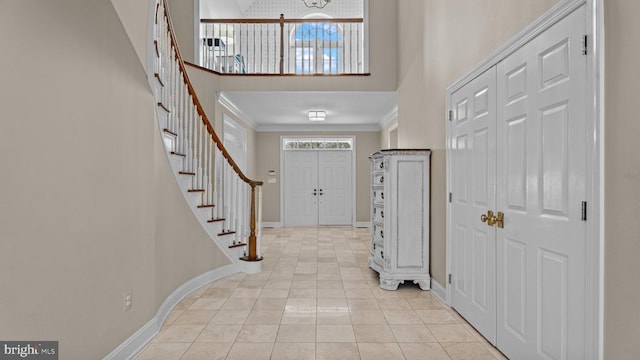 foyer with crown molding, baseboards, stairs, and a towering ceiling