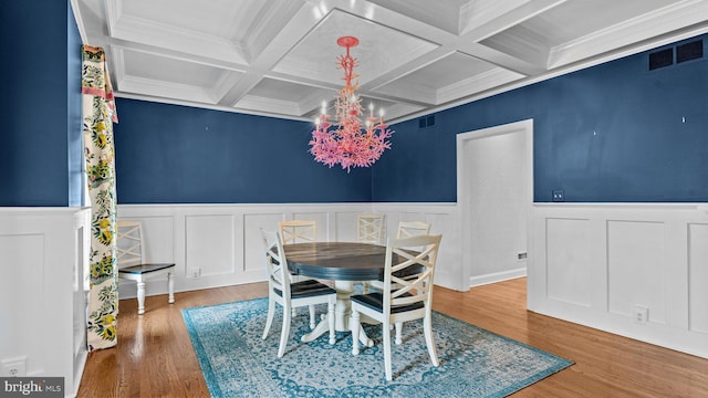 dining space with beam ceiling, a notable chandelier, visible vents, and wood finished floors