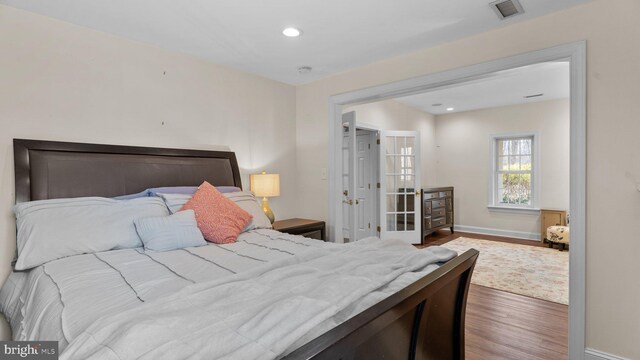 bedroom with recessed lighting, visible vents, baseboards, and wood finished floors