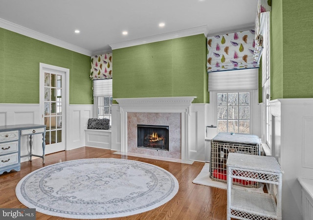 living room featuring a wainscoted wall, wood finished floors, a high end fireplace, and crown molding