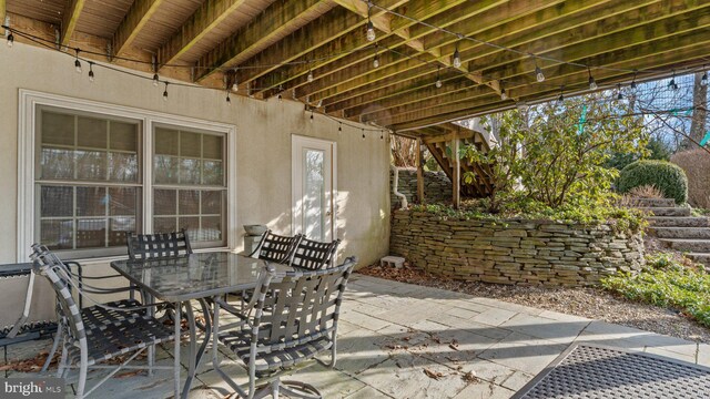 view of patio with outdoor dining space and stairs